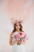 retrato de hermosa novia con flor guirnalda en su cabeza y nupcial ramo de flores foto