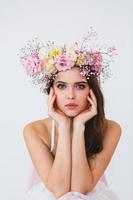 Portrait of beautiful bride with flower wreath on her head at white background photo