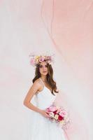joven novia en blanco vestir con flor guirnalda en su cabeza posando en el estudio foto