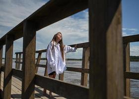 The girl stands on the shore and looks at the river. A woman is sitting by the river and enjoying the view. A sunny day. Background for the banner. photo