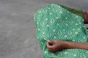 cerca arriba manos sostener verde tejido paño. hecho a mano tela textil. hermosa local mano tejido paño en tailandia diseñado y creado modelo para etnia moda. foto