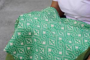 Close up hands hold green woven cloth. Handmade fabric textile. Beautiful local hand woven cloth in Thailand. Designed and created pattern for ethnicity fashion. photo