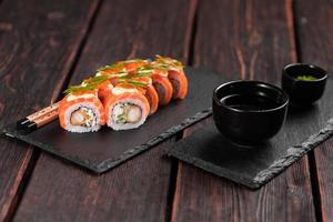 Sushi roll philadelphia with crab and cucumber and cream cheese, caviar on black background close-up. Sushi menu. Japanese food concept photo