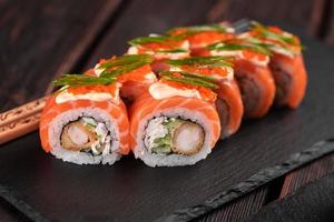 Sushi roll philadelphia with crab and cucumber and cream cheese, caviar on black background close-up. Sushi menu. Japanese food concept photo