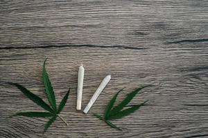 Joints with marijuana leaves on woodden table background. photo