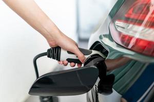 Woman plugged cable charging an electric car at home. photo