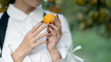 mujer granjero cosecha cuidadosamente maduro naranja en huerta. foto