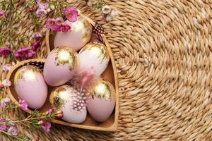 Easter decor. Easter eggs painted in gold in a heart-shaped wooden bowl. photo