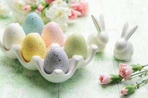 Easter decor. Colored Easter eggs on a ceramic stand and decorative rabbits. photo
