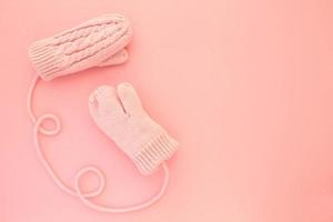 Close-up pink mittens and shaped of string on pink background. Lifestyle and warm feelings concept. Valentine day. Monocolor romantic pattern. Winter theme. Flat lay composition. Top view. Copy space photo