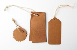 various brown paper tags with ropes on white background photo