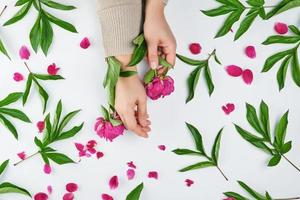 two hands of a young girl with smooth skin and a bouquet of red peonies photo