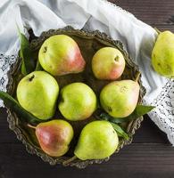 ripe green pears in an iron plate on a brown wooden table photo