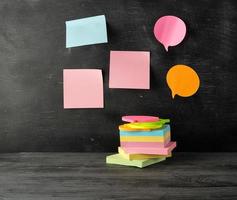 stack of multi-colored sticky stickers on a black wooden background photo