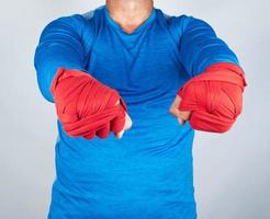 adult athlete in blue clothes, hands wrapped in a red elastic bandage photo