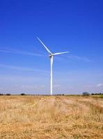 molino de viento en un campo contra un cielo azul foto