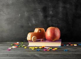 ripe red apple,  ancient toy car stand on a book photo