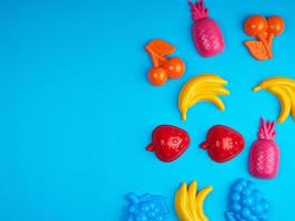 multicolored plastic toys fruits on a blue background photo