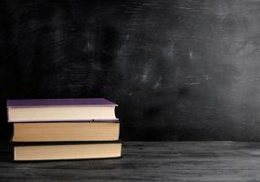 four closed books with yellow sheets on a black chalk board background photo