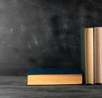 closed books with yellow sheets on a black chalk board background photo