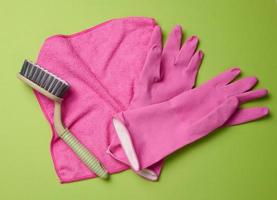 pink rug, rubber gloves for cleaning, brushes on a green background, flat lay. photo