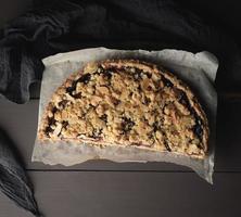 half plum pie crumble on a brown wooden cutting board photo