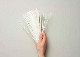 female hand holds a stack of plastic cable ties on a gray background. View from above photo