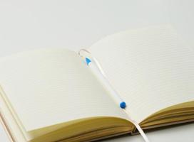 open blank notebook with pen on white table photo