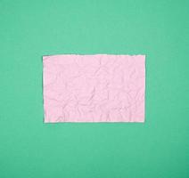 empty crumpled pink rectangular sheet of paper on a green background photo