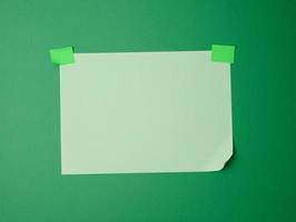 rectangular blank green sheet of paper glued with green sticky paper on green background photo