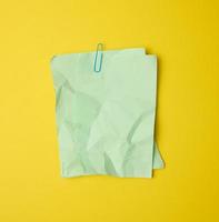 rectangular crumpled blank green sheet of paper on yellow background photo
