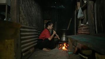 Blind Asian Women Blow the vintage fire stove with a piece of bamboo blower while cooking video