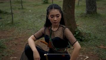 asiatisk kvinnor med svart kostymer och svart lång hår sitta mellan de träd video