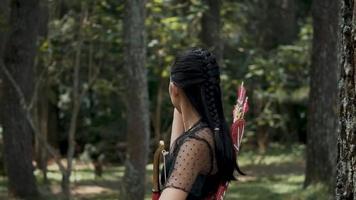 tiro com arco mulher perseguindo a inimigo dentro a selva com uma arco e seta dentro dela mãos video