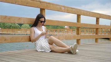 süße Frau liest SMS auf dem Handy, während sie im Park sitzt. video