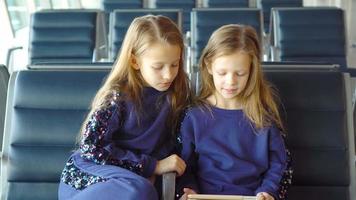 meninas adoráveis no aeroporto esperando para embarcar e brincar com o laptop video