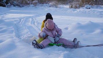 aanbiddelijk weinig gelukkig meisjes rodelen in winter besneeuwd dag. video