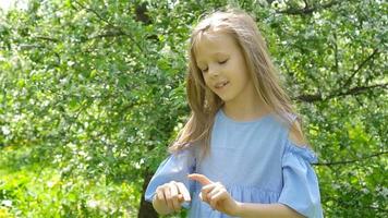 Little girl in blooming apple tree garden on spring day plays with ladybug video