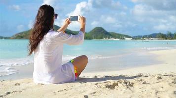 Young woman with phone on tropical beach. video