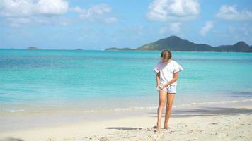 poco ragazza con bottiglia di sole crema seduta a tropicale spiaggia video