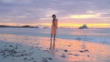 adorable petite fille heureuse sur la plage blanche au coucher du soleil video