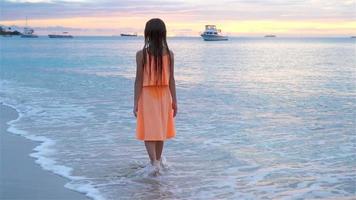 sihouette av liten flicka på de strand på solnedgång. video