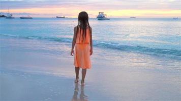 sihouette do pequeno menina em a de praia às pôr do sol. video