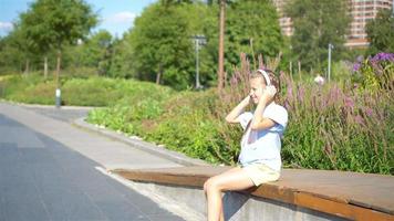 petite fille adorable écoutant de la musique dans le parc video