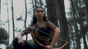 Frau Bogenschießen halten ein Bogen und ein Pfeil im das Urwald Jagd zum Feind