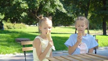 poco ragazze mangiare gelato all'aperto a estate nel all'aperto bar video