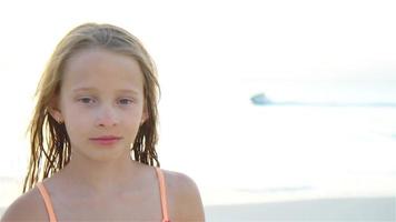 retrato de pequeño niña mirando a cámara y sonriente antecedentes cielo y mar. video