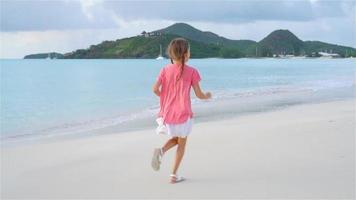 sihouette de niña caminando por la playa al atardecer. video