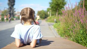 Little adorable girl listening music in the park video