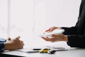 Hand holding car keys and car rental concept A close-up view of the agent, giving the customer the car keys after signing the lease, rental form and car name. photo